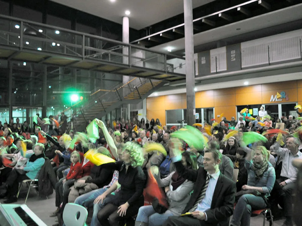 Zuschauer schwenken Tücher im abgedunkelten Foyer.